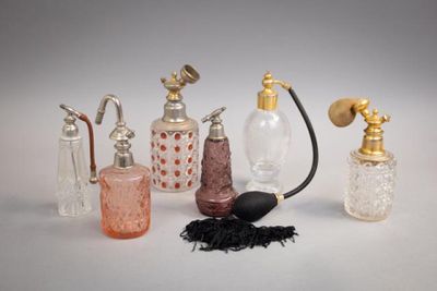 cinq types différents de flacons de parfum posés sur une surface blanche