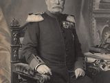 portrait of a man in uniform sitting in a chair in front of a desk