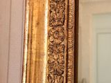 a large mirror with a gold frame on the wall