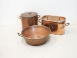 three copper pots and pans sitting on a table
