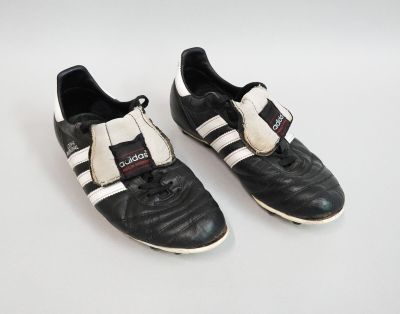 une paire de chaussures de foot noires et blanches posées sur une surface blanche