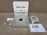 Un Mac mini d'Apple est posé sur une table, à côté d'une boîte