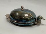 a silver plate with a bird on it on a white surface