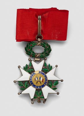 a close up of a medal on a red ribbon with a wreath