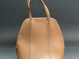 a tan handbag sitting on top of a gray surface