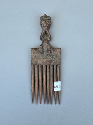 un petit peigne en bois surmonté d'un singe