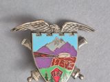 une image représentant un insigne métallique avec un aigle et une montagne en arrière-plan