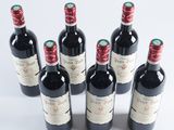 six bottles of wine are lined up in a row on a white surface