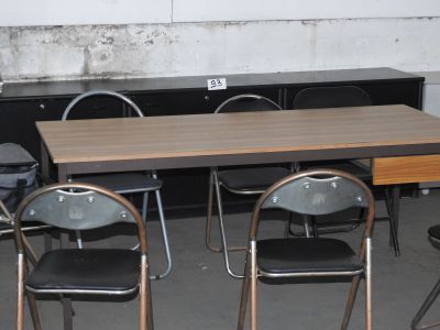 une table et des chaises dans une pièce, avec un mur derrière elles