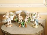quatre figurines posées sur une table sur laquelle se trouve un vase