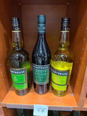 Trois bouteilles d'alcool sont posées sur une étagère dans un magasin.