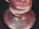 a red and white vase sitting on top of a metal stand