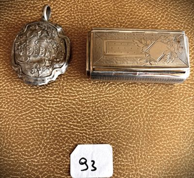 two small silver objects are sitting next to each other on a brown leather surface