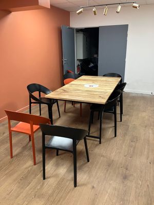 tables and chairs in a room with orange walls and wood flooring