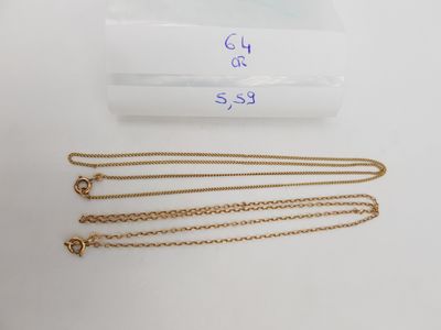 Deux chaînes en or et un collier sont posés sur une table