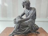 a statue of a woman sitting on top of a wooden table