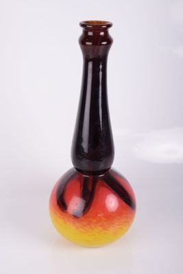 un vase rouge et jaune posé sur une surface blanche