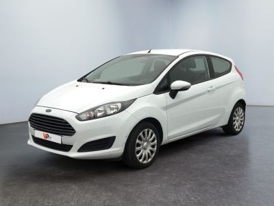 La Ford Fiesta blanche est garée dans une pièce au sol noir.