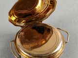 a small gold pocket watch sitting on top of a table