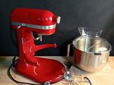 un batteur rouge posé sur une table en bois, à côté d'un saladier