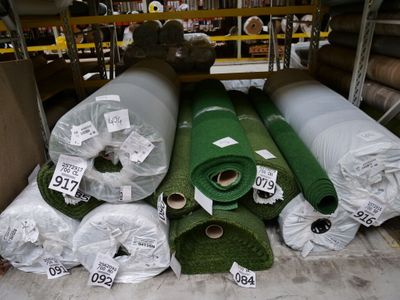 Plusieurs rouleaux de gazon synthétique sont empilés les uns sur les autres dans un entrepôt
