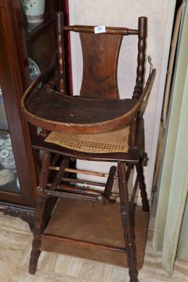 une chaise haute en bois avec une assise en osier, placée devant un meuble