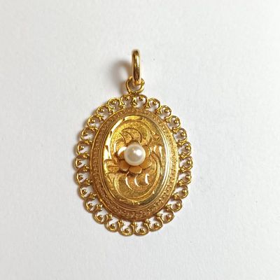 un gros plan d'un pendentif en or orné d'une perle au centre