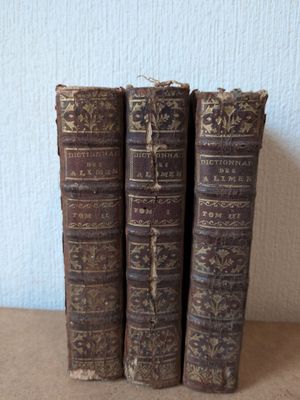 trois vieux livres posés sur une table l'un à côté de l'autre