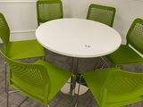 a white table with four green chairs around it