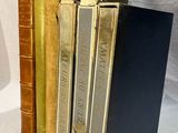 several old books are stacked on top of each other on a white surface