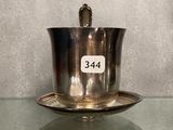 une tasse et une soucoupe en argent posées sur une table en verre