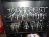 une étagère noire sur laquelle sont posés des verres à vin et des assiettes