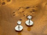 pair of silver earrings sitting on top of a burlock wood table