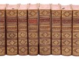 six vieux livres sont alignés sur une surface blanche