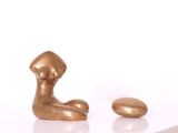 une figurine en or posée à côté d'un œuf sur une surface blanche