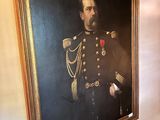 portrait of a man in a military uniform in a room with a painting on the wall