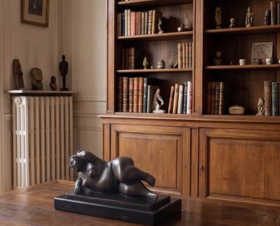 a statue of a dog on a table in front of a bookshelf
