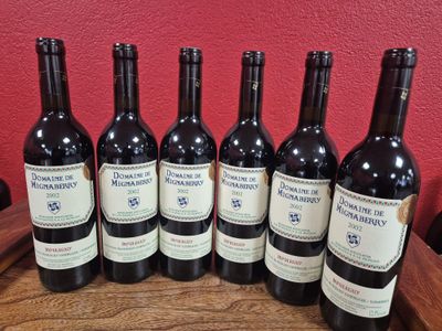 six bouteilles de vin rouge sont alignées sur une table en bois