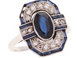 gros plan d'une bague avec une pierre bleue entourée de diamants