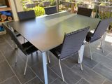 une table et des chaises sur une terrasse, avec un balcon en arrière-plan