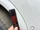 a person holding a ruler that is on the side of a car