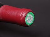a close up of a red wine bottle with a green cap