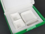 a green box with four white dishes inside of it