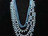 a necklace with turquoise beads and pearls is displayed on a mannequin