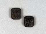 deux petits boutons noirs placés l'un à côté de l'autre sur une surface blanche