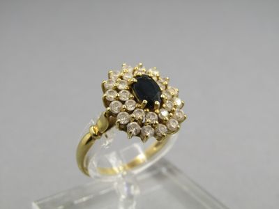 a close up of a gold ring with a black stone surrounded by white diamonds