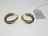 a pair of gold hoop earrings on a white surface
