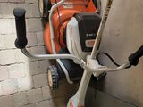 an orange and white lawn mower sitting on top of a brick wall