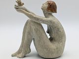statue of a woman sitting on her knees holding a flower