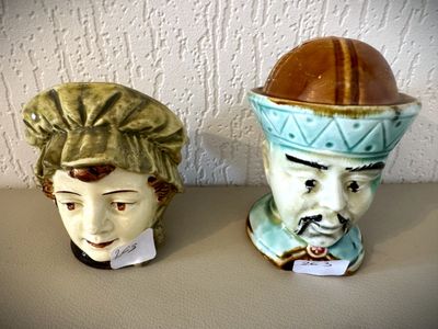 deux vases ornés de visages, posés sur une table